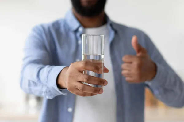 A man smiling while enjoying a glass of good water